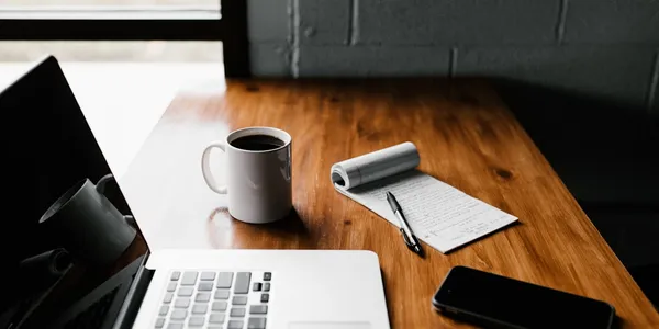 A journal and coffee on a warm wooden desk